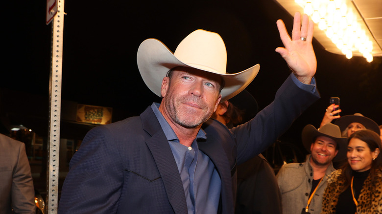 Taylor Sheridan in a cowboy hat waving