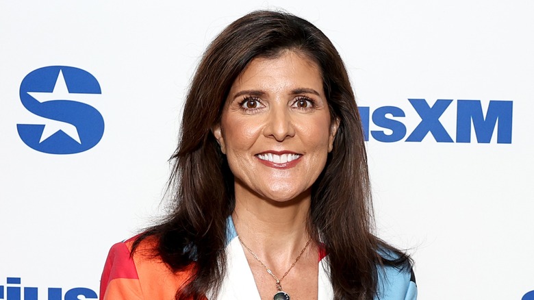 Nikki Haley smiling in a blazer with one orange and one blue shoulder
