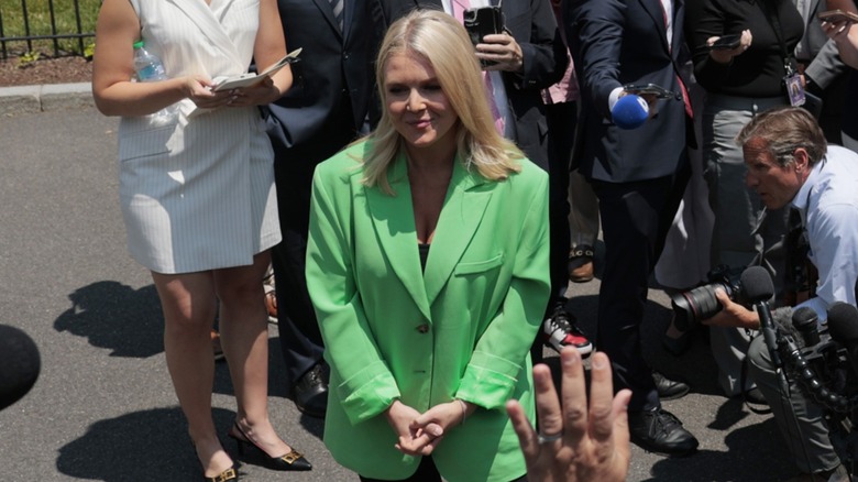 Karoline Leavitt speaking to the press with her hands clasped in front of her, while wearing an ill-fitting, neon green blazer (2025)