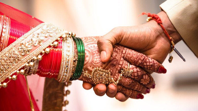 Indian bride and groom hold hands