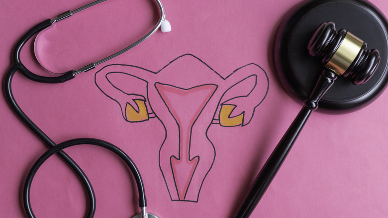 female reproductive system with a stethoscope and gavel on a pink background