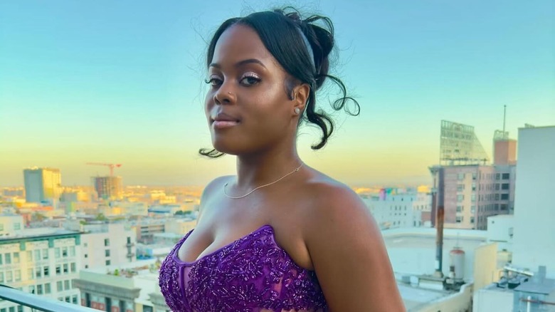 Alysha Burney poses on a balcony wearing a purple gown.