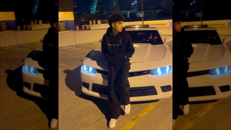 Gabriel Salazar in black hoodie leans against a white car at night