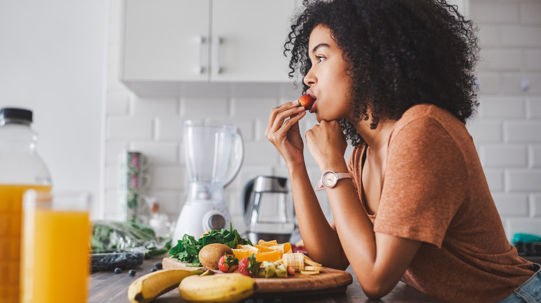 woman eating fruit in kitchen
