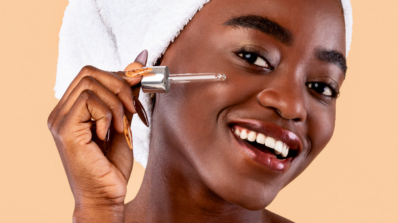 Smiling woman applying skin serum