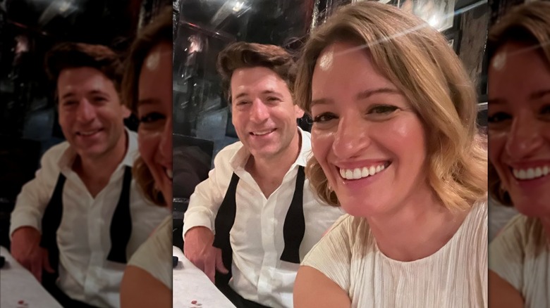 Katy Tur smiles while taking a selfie seated beside Tony Dokoupil, who wears an undone black bowtie.