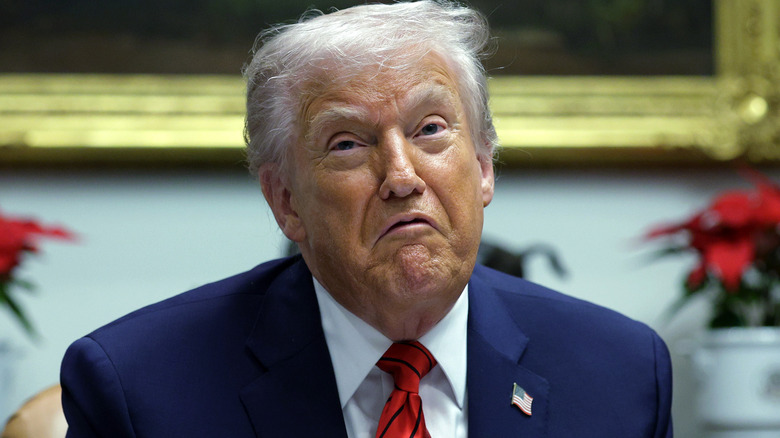 Donald Trump looking very displeased in a navy suit with a red tie