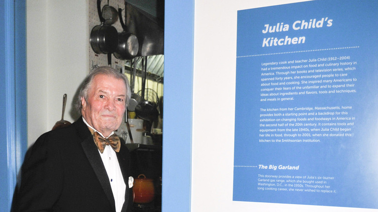Jacques P﻿épin poses in front of Julia Child's kitchen in the Smithsonian Institute.