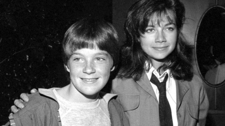 Black and white photo of Justine Bateman wearing a tie with her arm around Jason