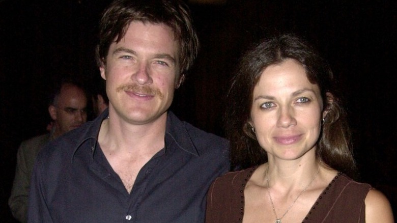 Jason Bateman with mustache in black shirt with Justine Bateman in brown v-neck dress