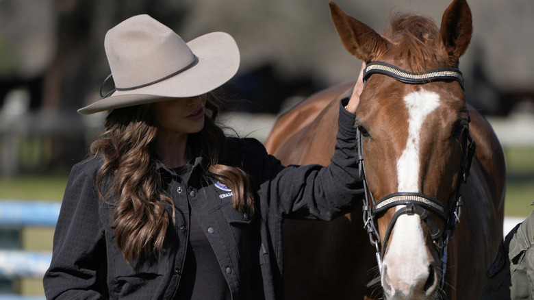 Kristi Noem petting a horse in July 2025