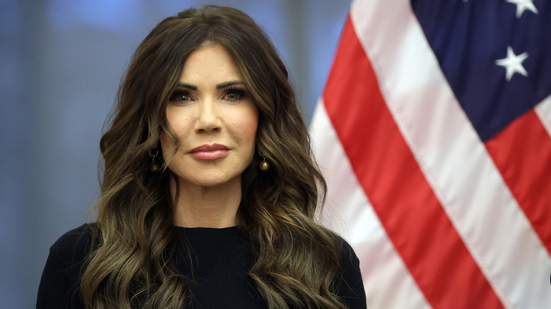 Kristi Noem in front of the American flag in 2026