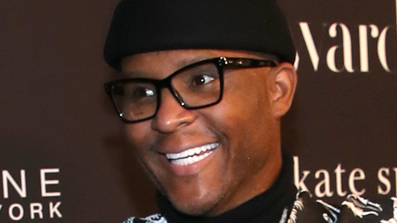 Law Roach wears a black beanie and glasses and smiles.