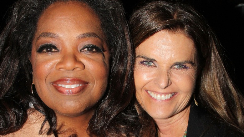 A closeup of a smiling Oprah and Maria Shriver