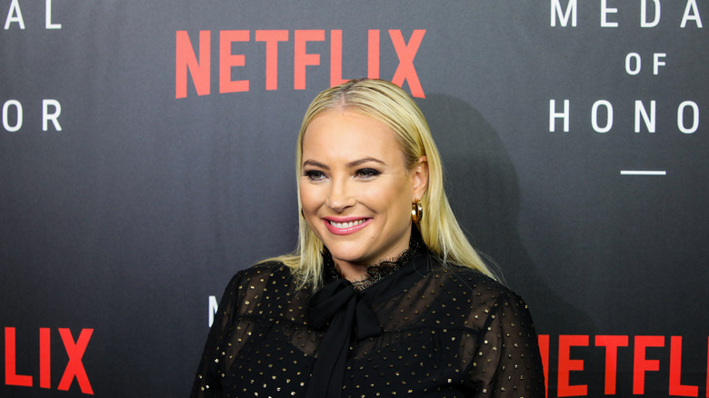 Meghan McCain smiles in front Netflix banner