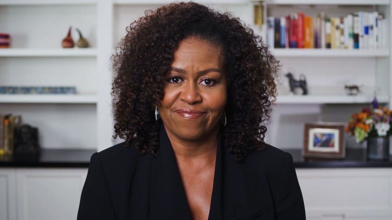 Michelle Obama wearing black outfit in front of bookshelves