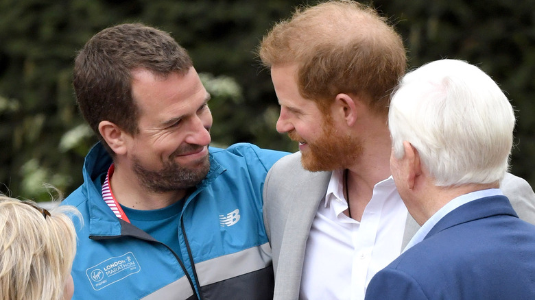 Peter Phillips and Prince Harry smiling at each other