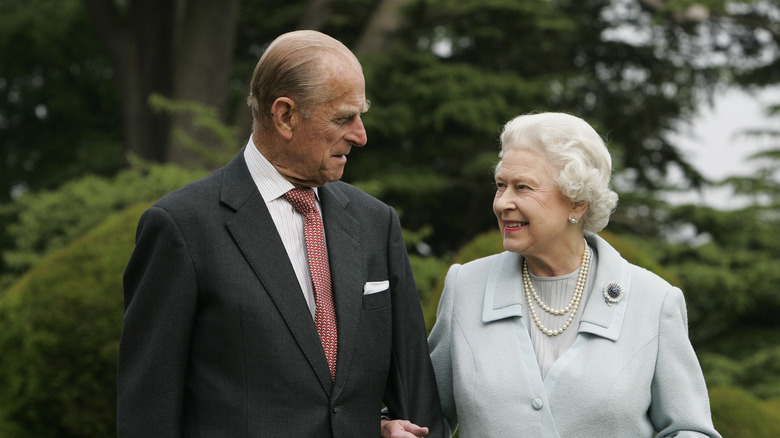 Queen Elizabeth and Prince Philip smiling and looking at each other