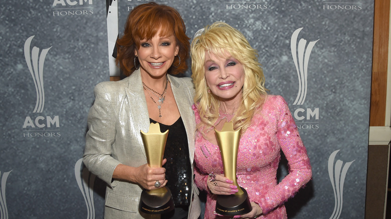 Reba McEntire and Dolly Parton holding awards