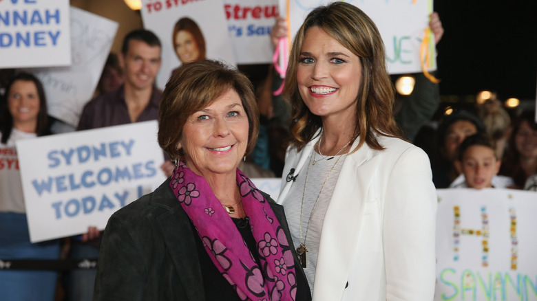 Nancy and Savannah Guthrie smiling for cameras in front of a crowd of fans with signs