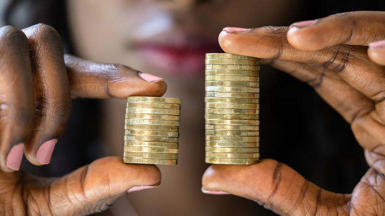 Woman holding two unequal sets of coins