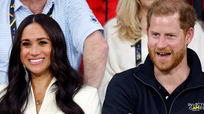 Meghan Markle and Prince Harry smiling at sporting event