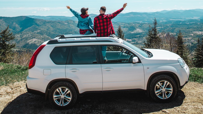 Couple popping out of sunroof, arms raised