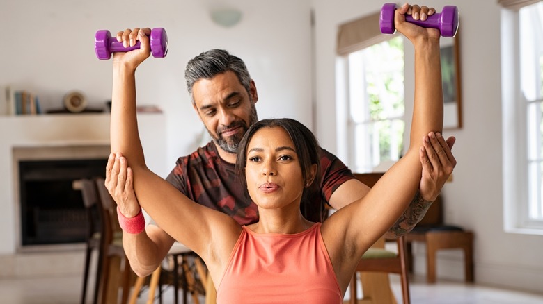 Woman lifting weights with trainer