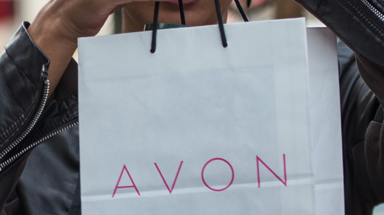 An Avon sales representative holding a beauty bag
