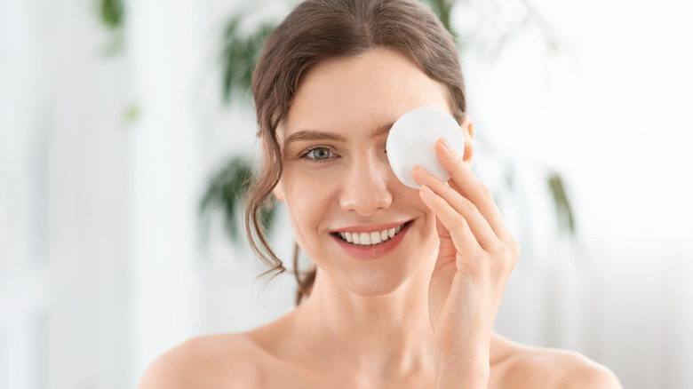 A woman removing her makeup with a cotton pad