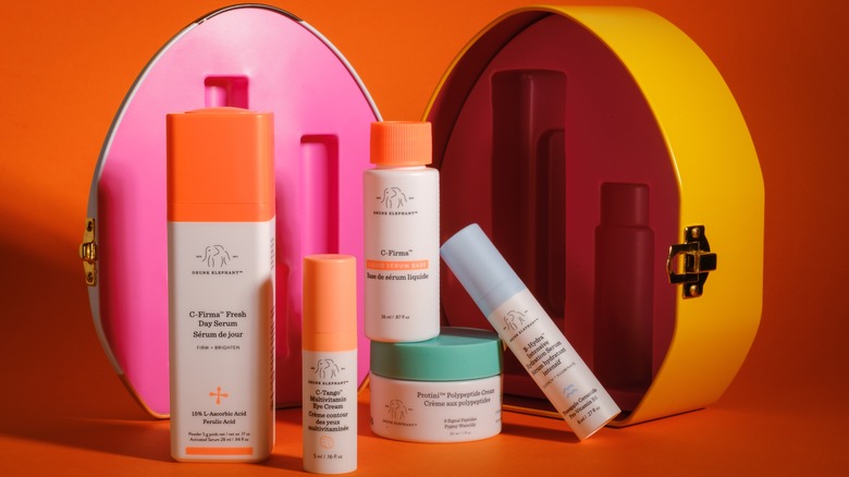 Various Drunk Elephant beauty products against an orange backdrop