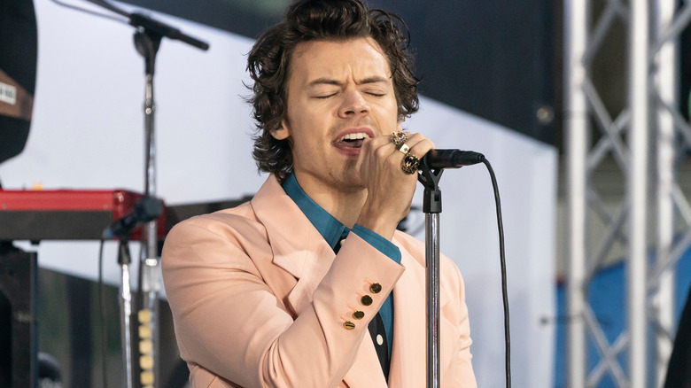 Harry Styles performing onstage in a peach blazer