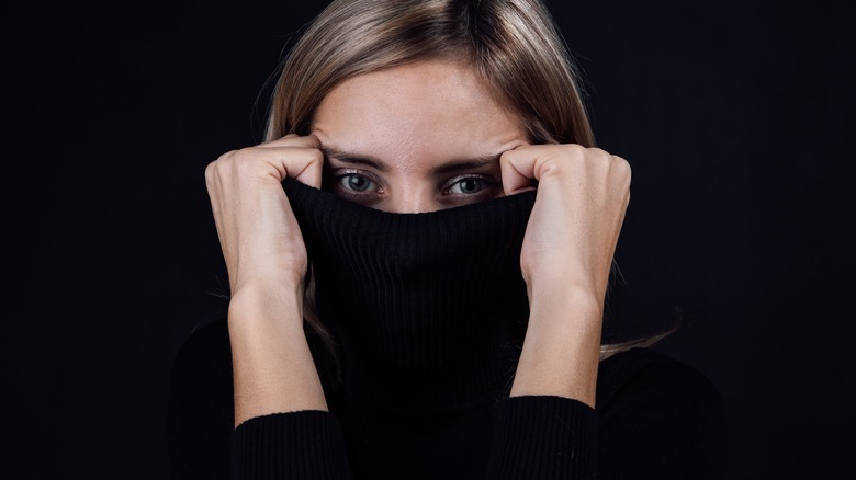 Woman covering face with turtleneck