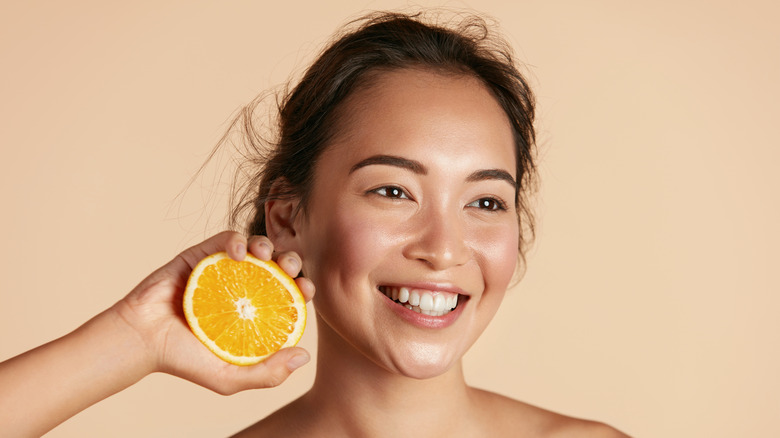 Woman holding orange and smiling