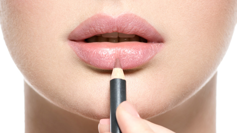 Lip liner pencil against woman's lips