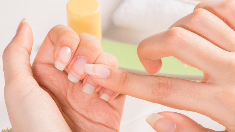 woman applies cuticle oil to her nails 