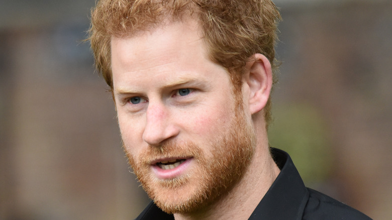 Prince Harry wears a black shirt at an event.