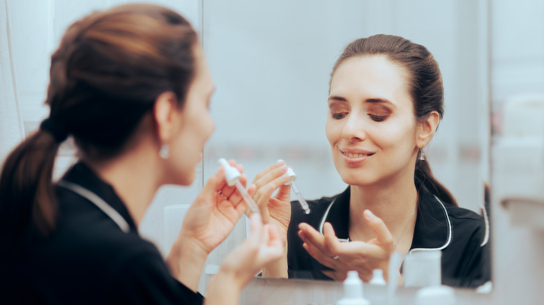 woman applying serum in bathroom