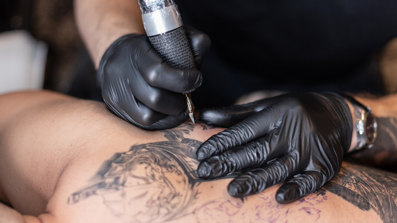 Tattoo artist giving someone a tattoo