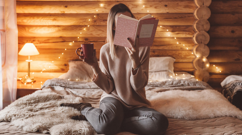 Woman reading a book in a cozy bed
