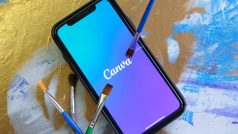 Smart phone surrounded by paintbrushes showing Canva logo