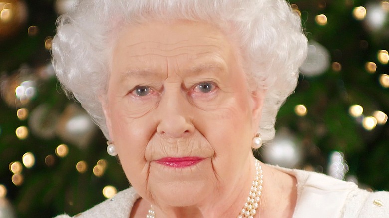 Queen Elizabeth poses in front of a Christmas tree 