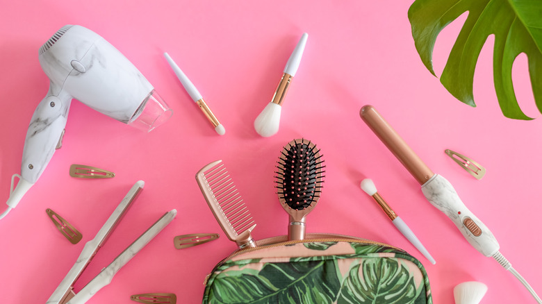 Beauty styling tools laying flat on pink table
