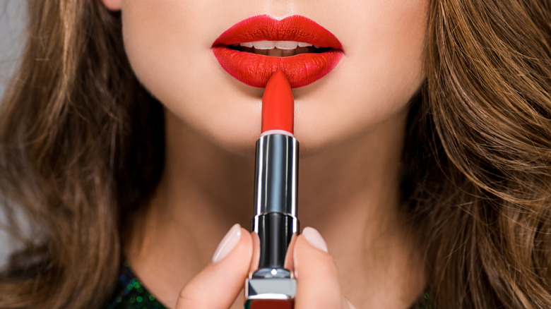 Young woman with red lips holding red lipstick