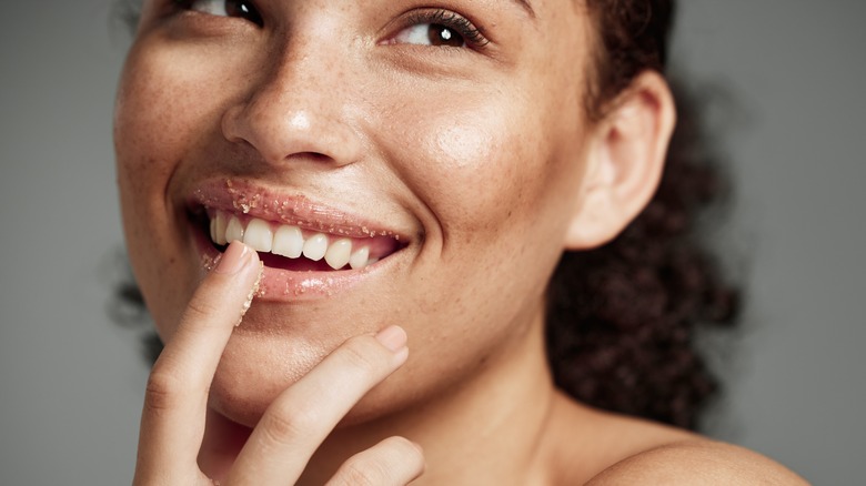 Woman applying sugar scrub on lips