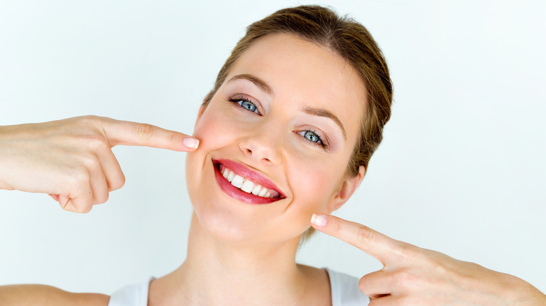 Woman pointing to her white teeth