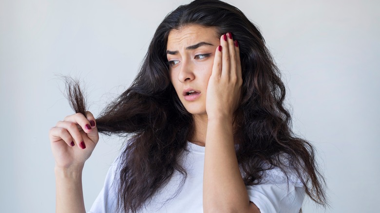 Stressed woman looking at her damaged hair