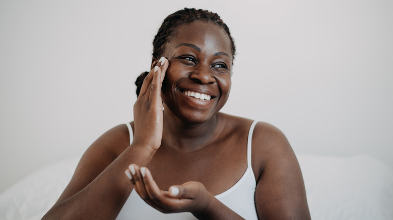 Smiling woman applies face cream