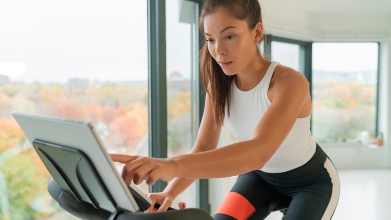 Woman touching screen on stationary bike