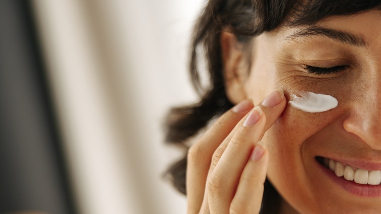 Woman putting moisturizer on face